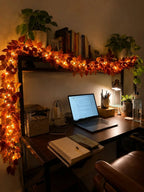 Autumn leaf garland with fairy lights brightening a desk and bookshelf corner