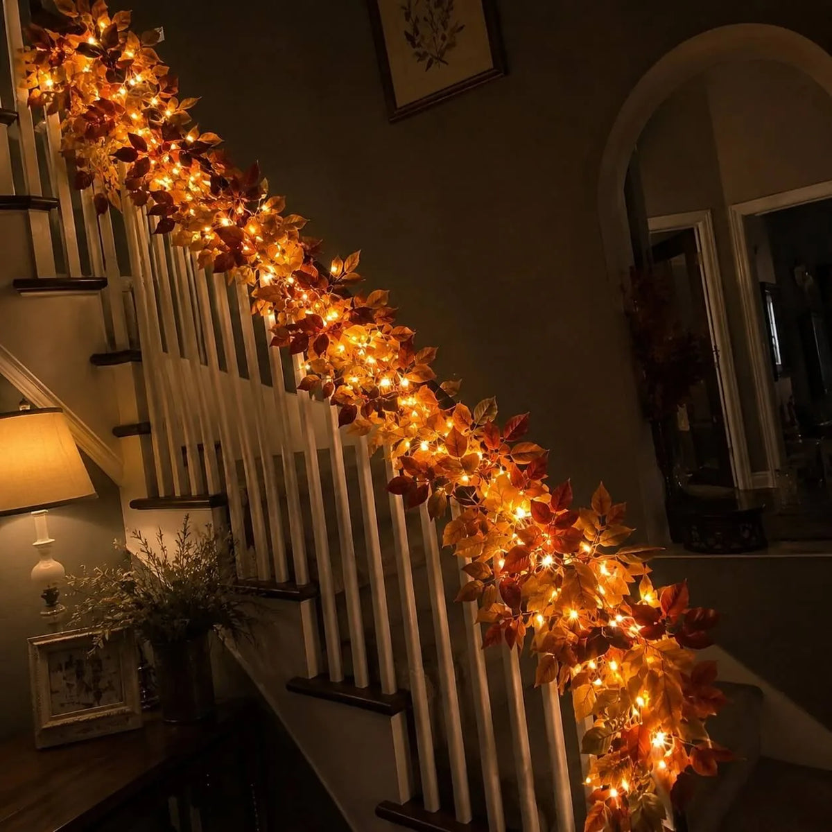 Autumn leaf garland with fairy lights cascading down a staircase railing